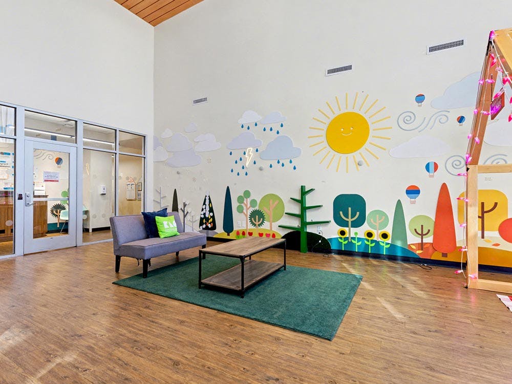 Lobby with a couch, coffee table, and colorful mural on the wall