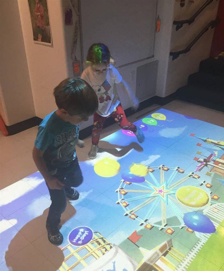 Two children playing on an interactive floor projection