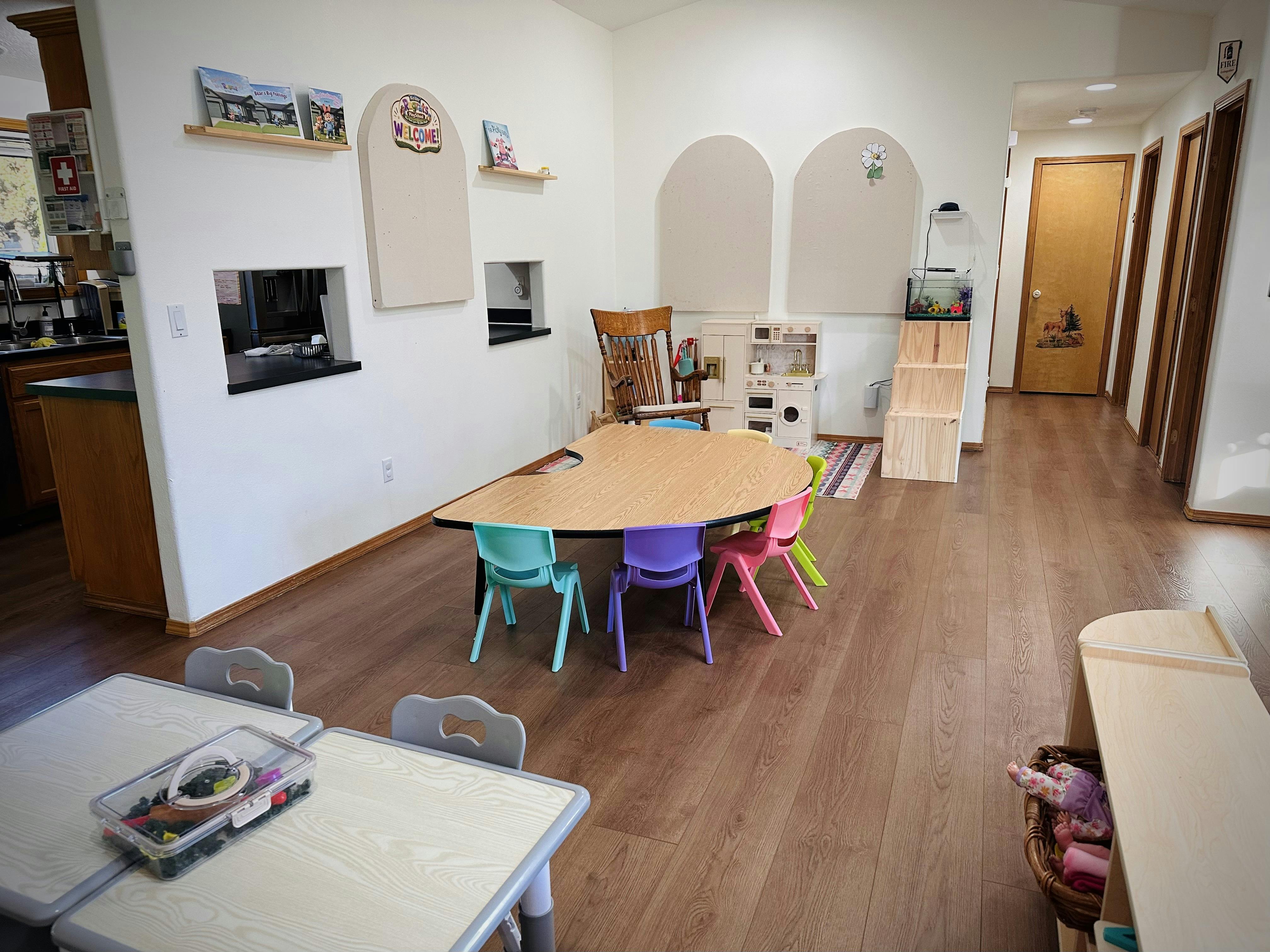 Playroom with a crescent-shaped table, colorful small chairs, and toy furniture