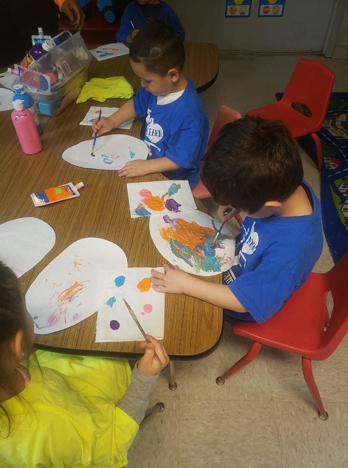 Children painting at a table in a classroom