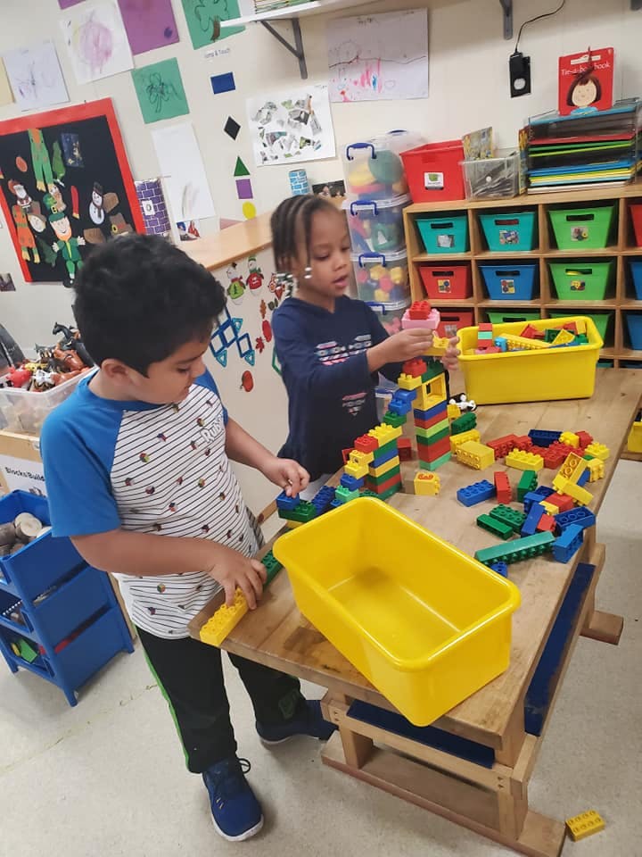 Two children playing with colorful building blocks at a table