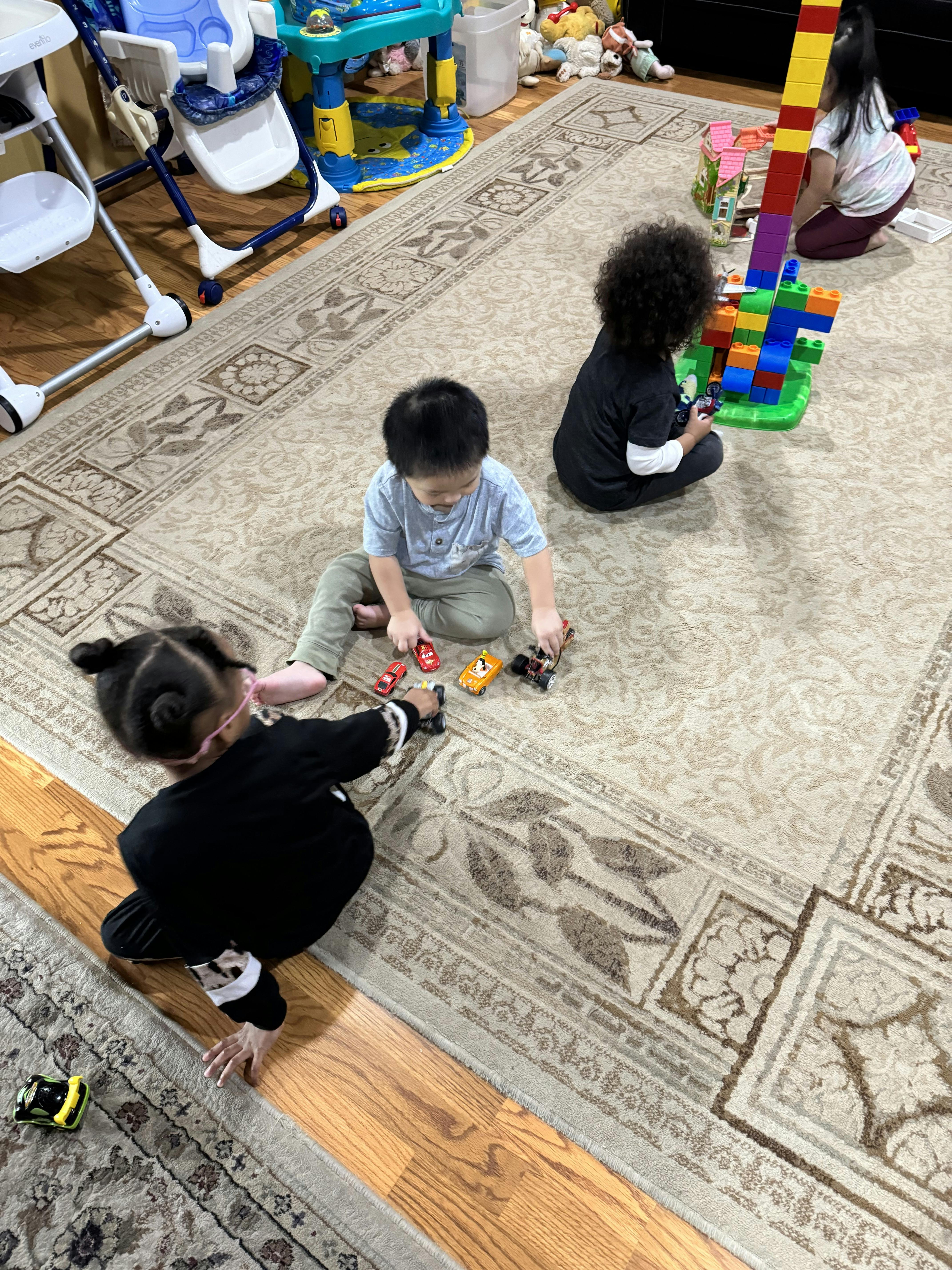 Three children playing with toys on a rug