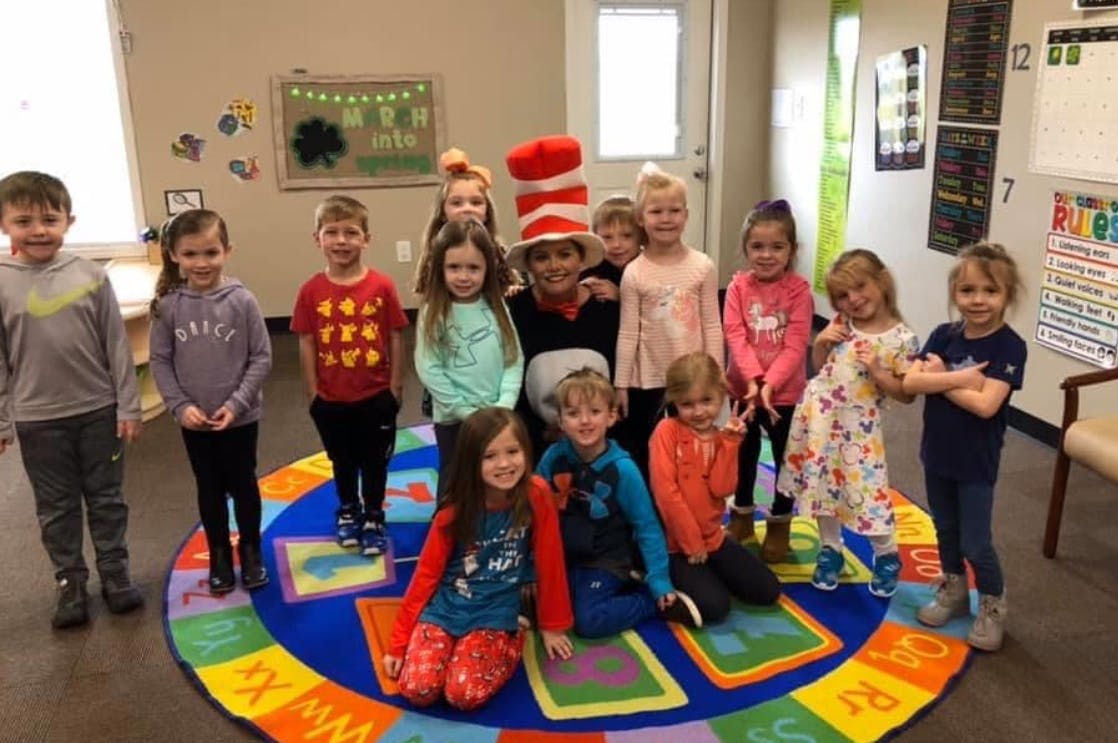 Group of children and one adult in a tall red and white striped hat