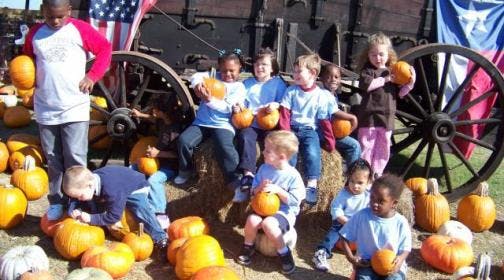 Children holding and sitting on pumpkins