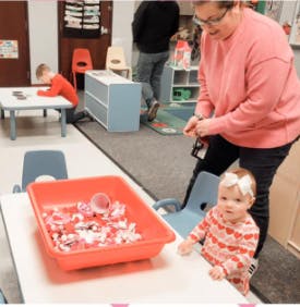 Adult and child in a classroom with a sensory bin