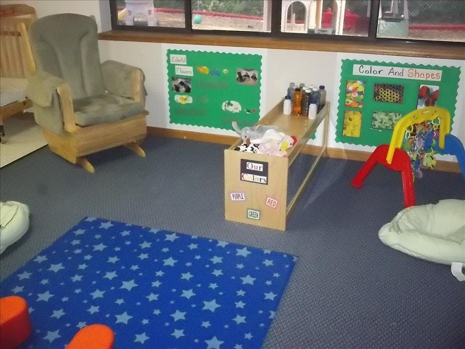 Rocking chair, activity mats, and a play area in a daycare classroom