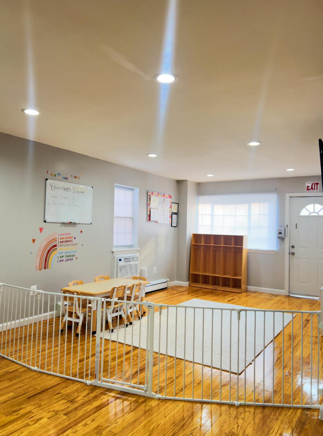 Playroom with a small table and chairs, a white safety gate, and hardwood floors