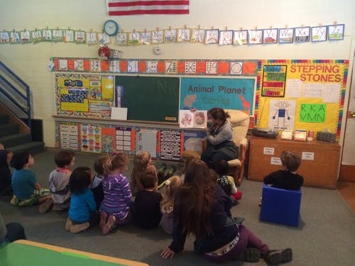 Person reading a book to children in a classroom