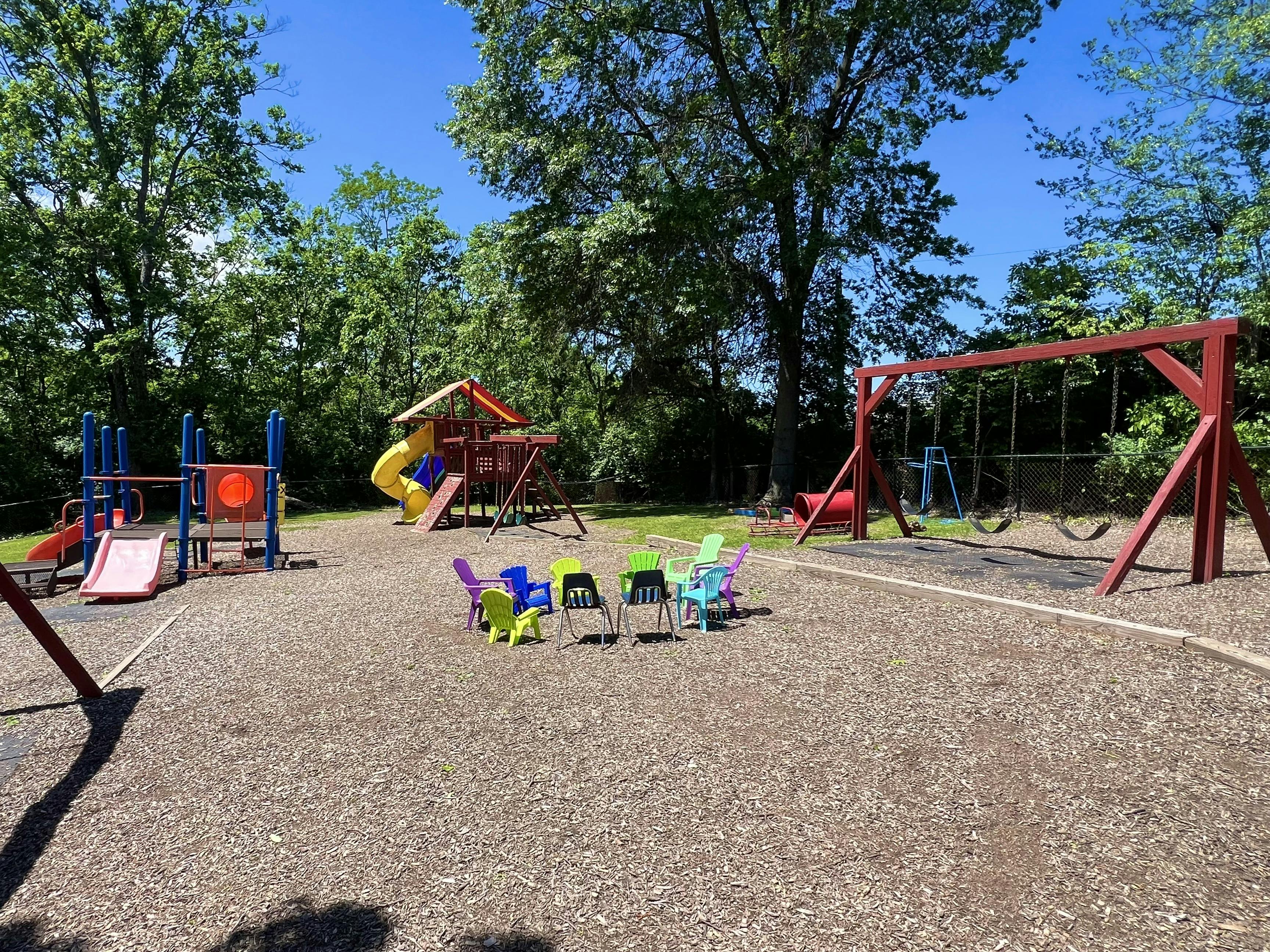 Outdoor playground with slides, swings, and small chairs