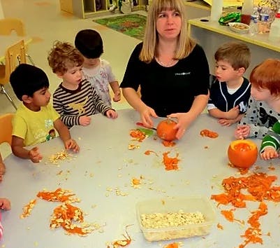 Adult and children carving pumpkins at a table
