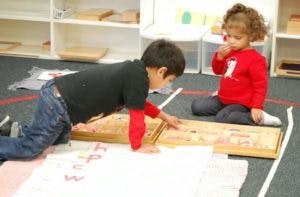 Two children playing with wooden blocks on the floor