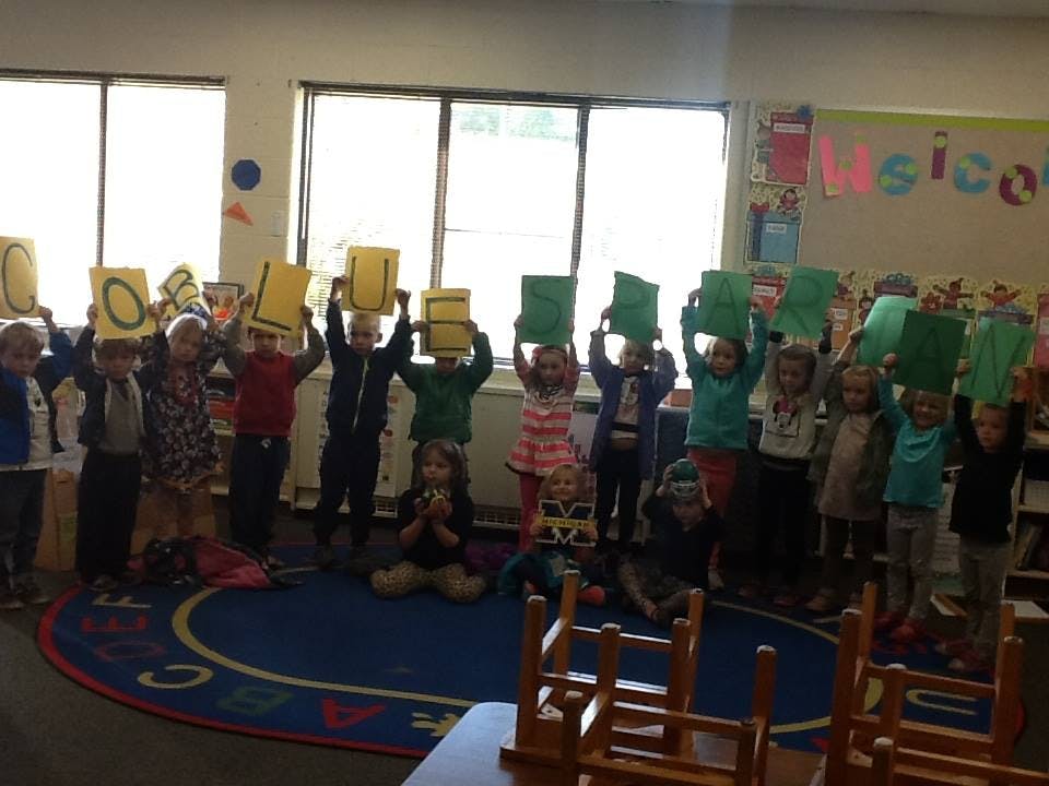 Children holding up yellow and green papers in a classroom