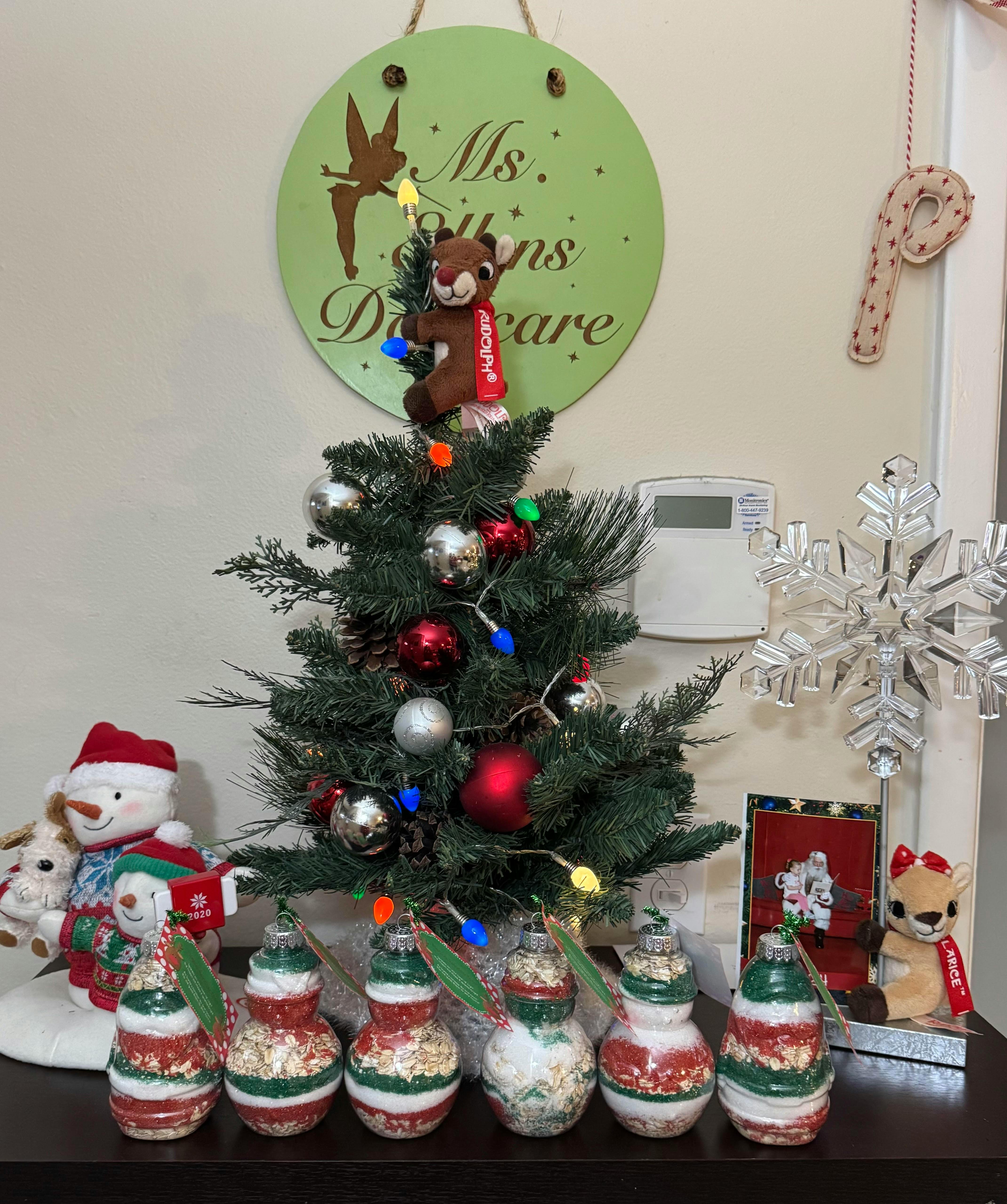 Small decorated Christmas tree with ornaments and lights, a snowman, and decorative gourds