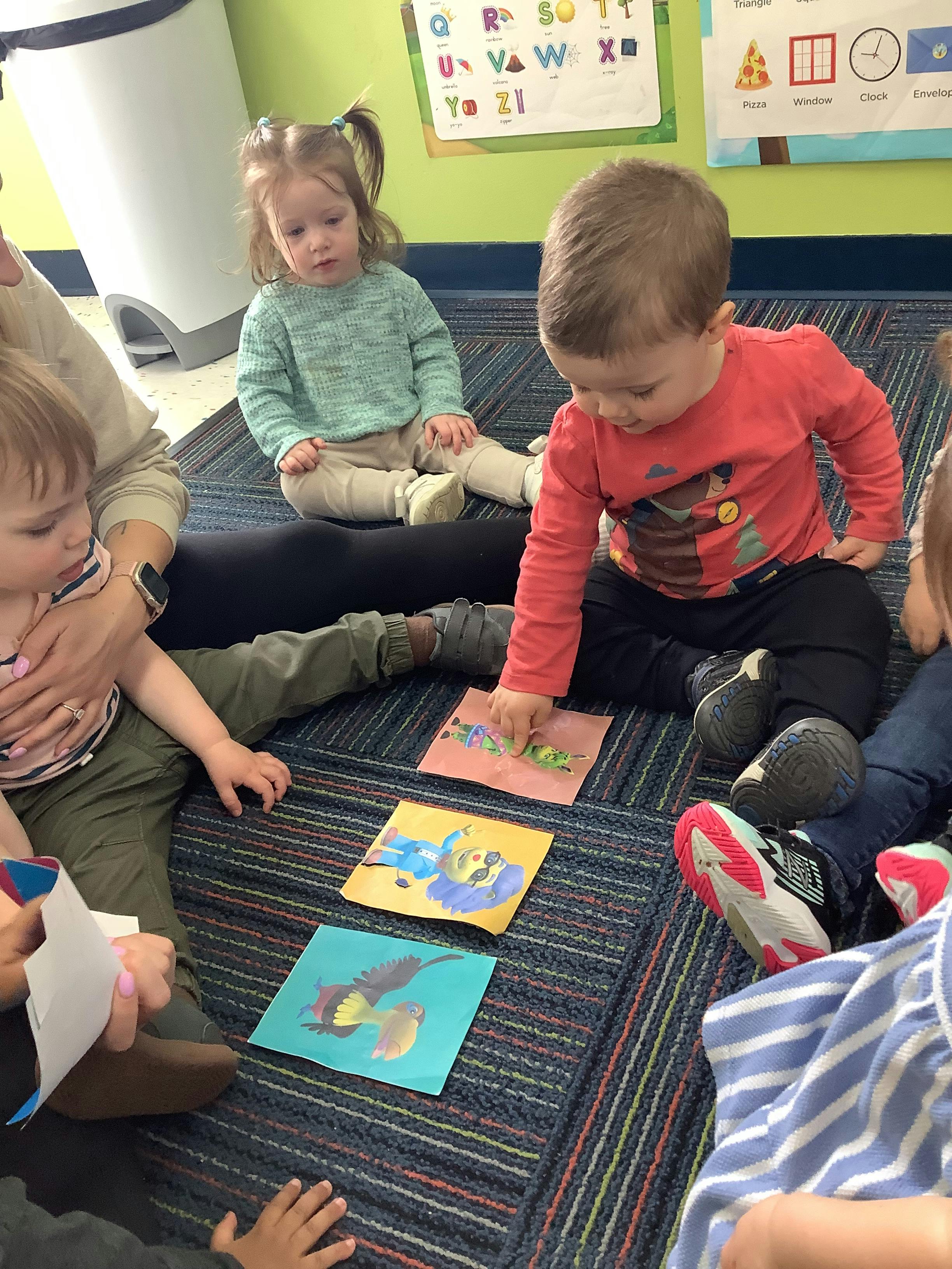 Children sitting on a rug looking at colorful cards