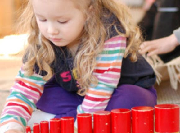 Child playing with red stacking cylinders
