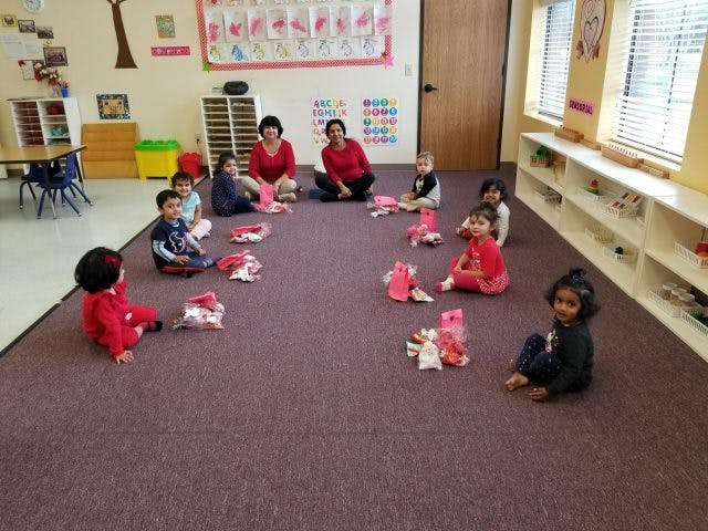 Adults and children sitting on the floor in a classroom
