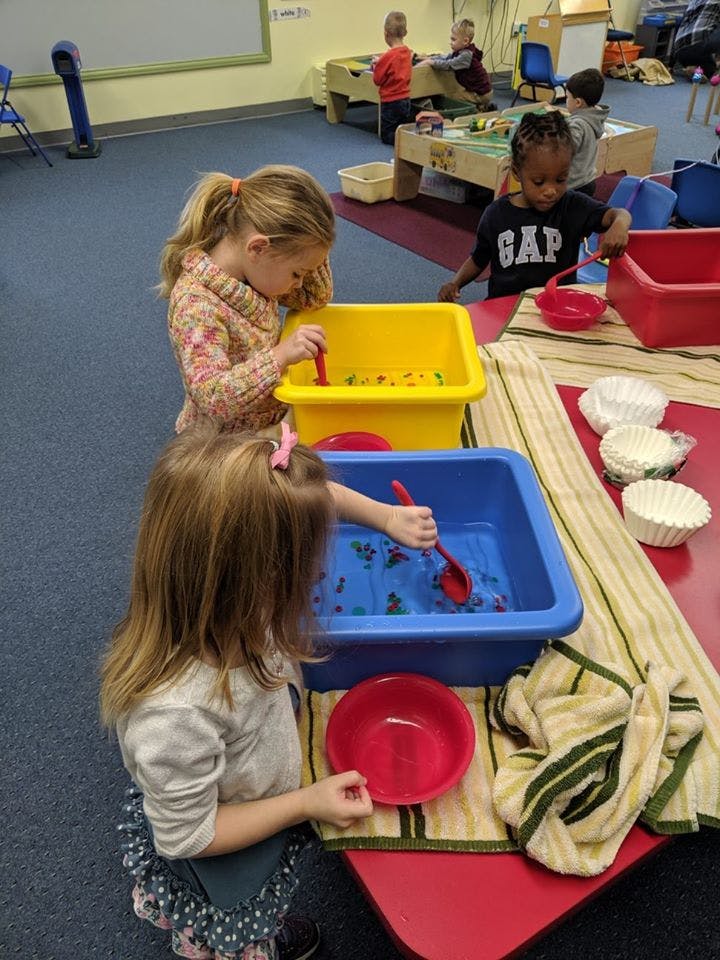 Children playing with water and toys in plastic bins in a classroom