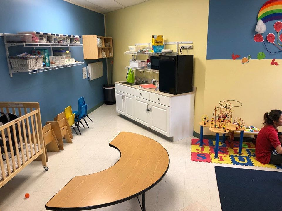 Classroom with crib, small chairs, and person sitting on floor