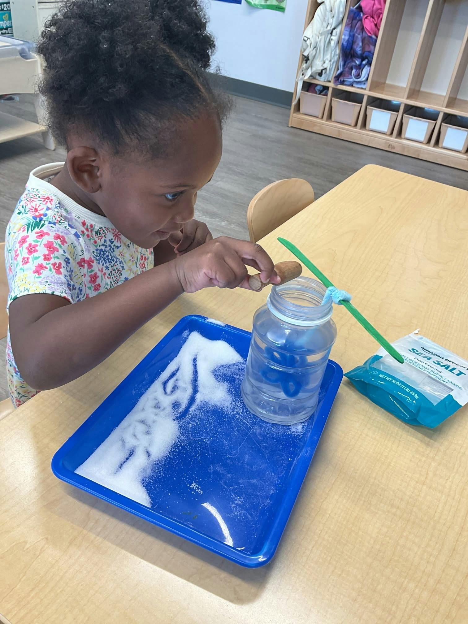 Child performing a salt crystal science experiment at a classroom table