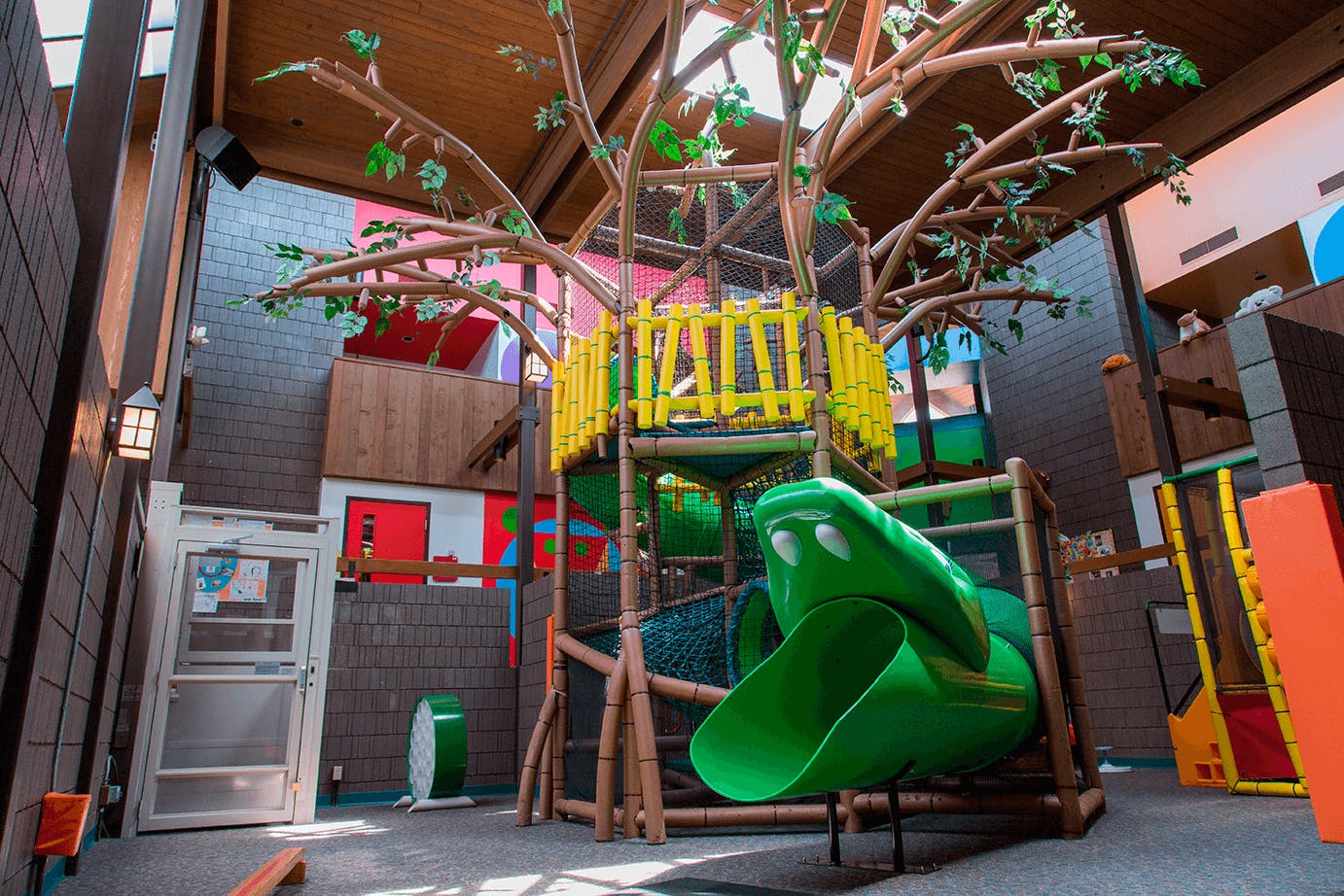 Indoor playground with a treehouse structure and green slide