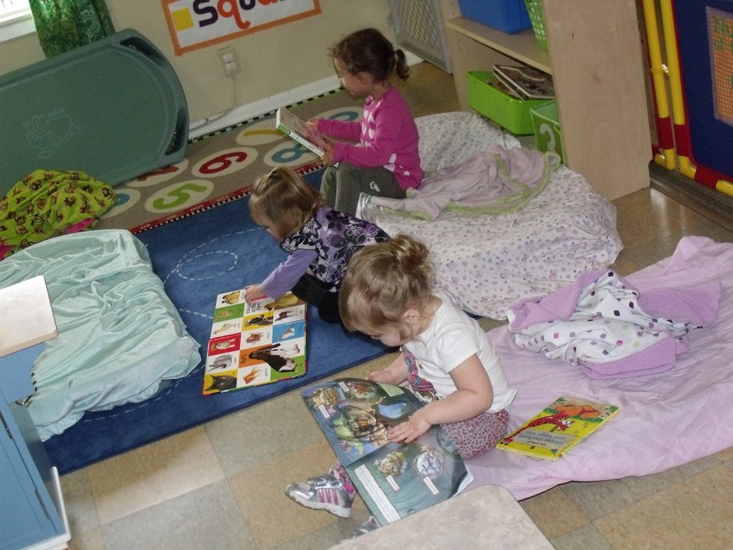 Three children reading books on the floor