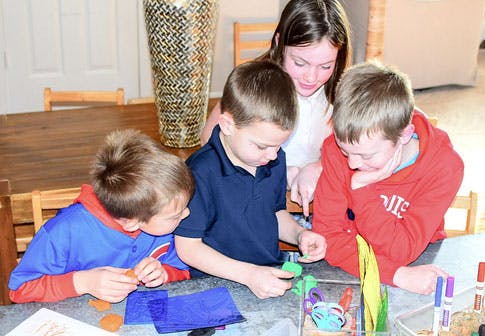 Four children gathered around a table doing crafts