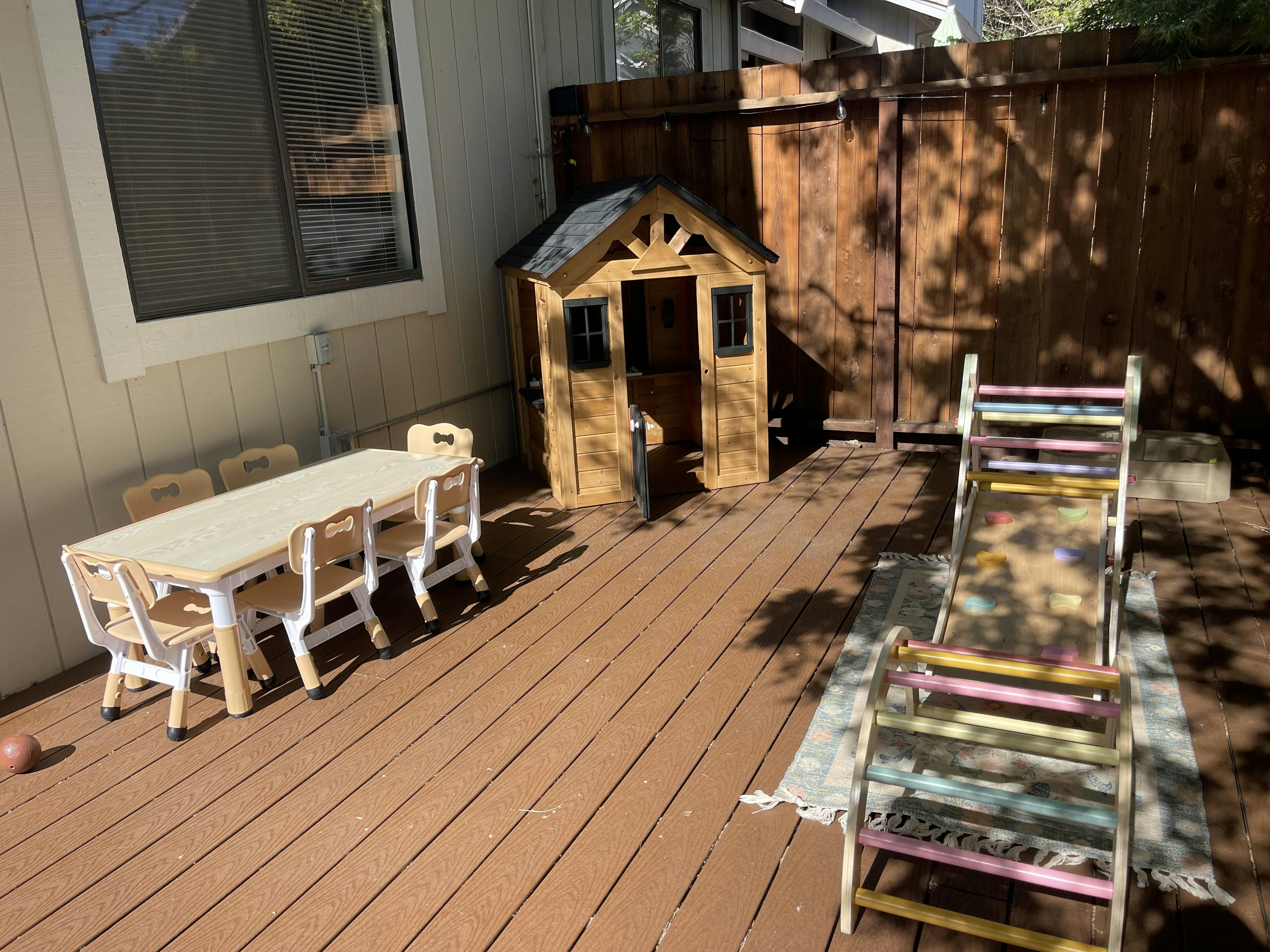 Children's playhouse, table, chairs, and climbing frame on an outdoor deck