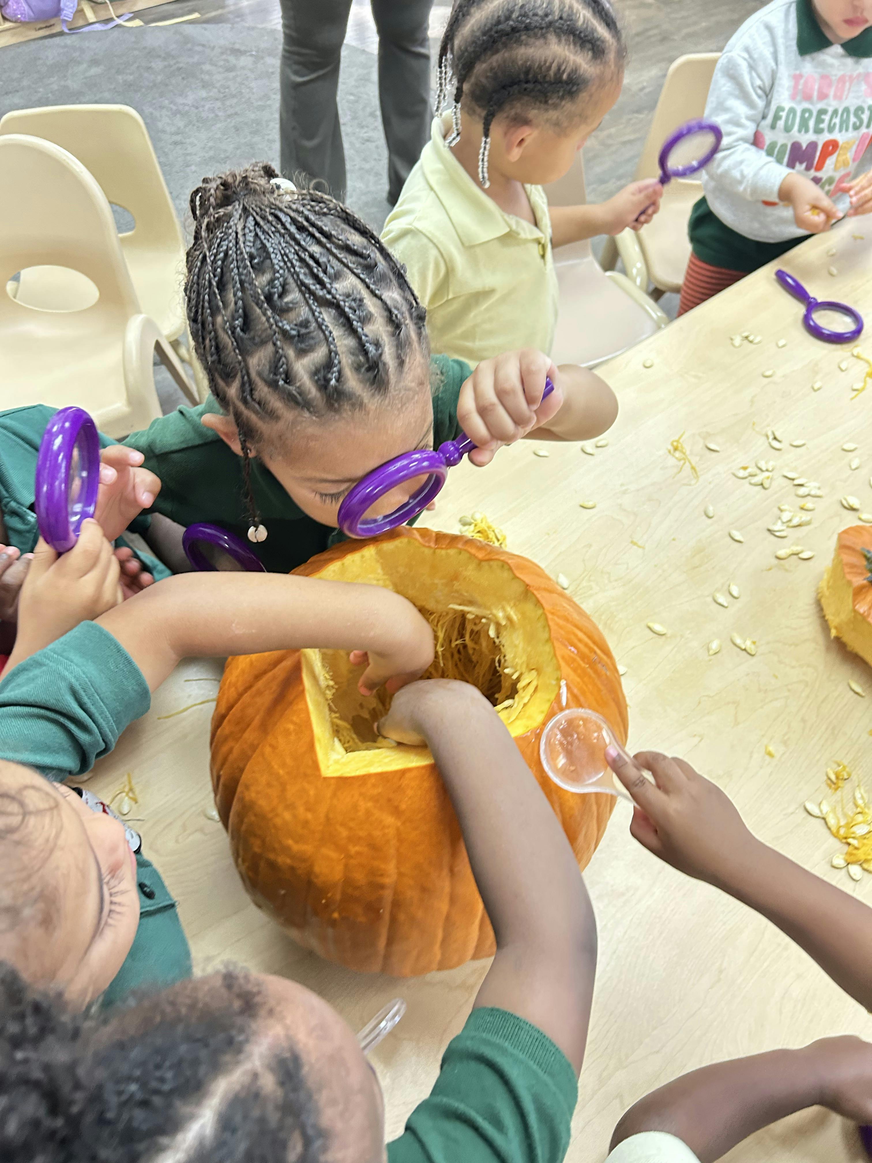 Children carving a pumpkin with magnifying glasses