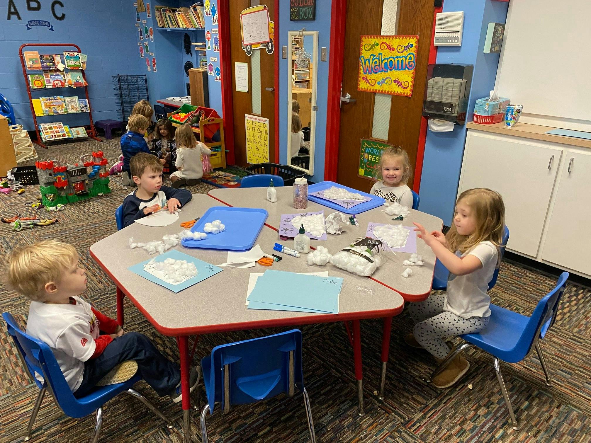 Children doing crafts at a table in a classroom