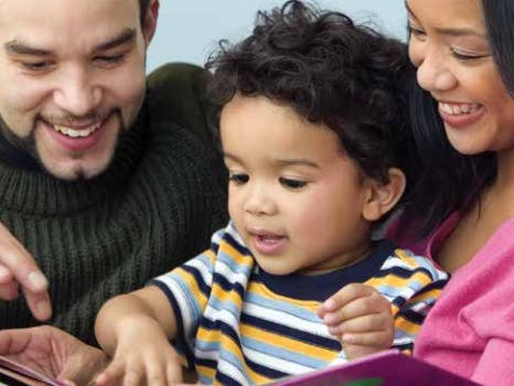 Two adults and a child looking at a book