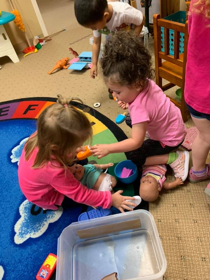 Children playing with dolls on a rug