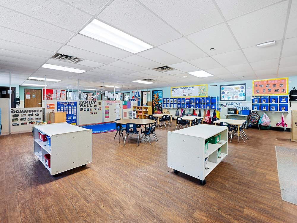 Classroom with small tables and chairs, shelves, and learning materials on walls