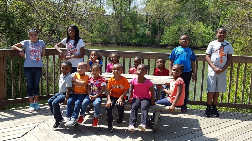 Group of children and teens posing on a wooden deck near water