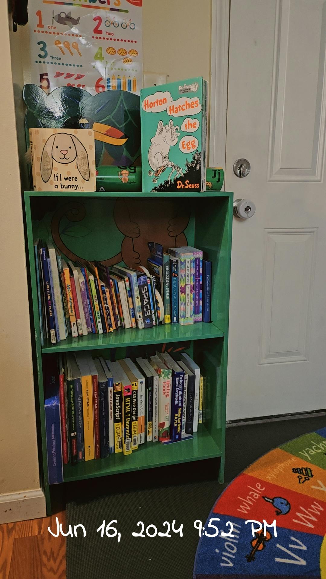 Green bookshelf with books, a numbers chart, and a door