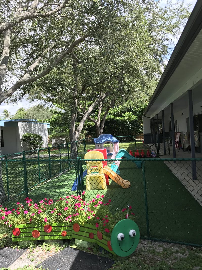 Outdoor playground with colorful slides and a caterpillar planter