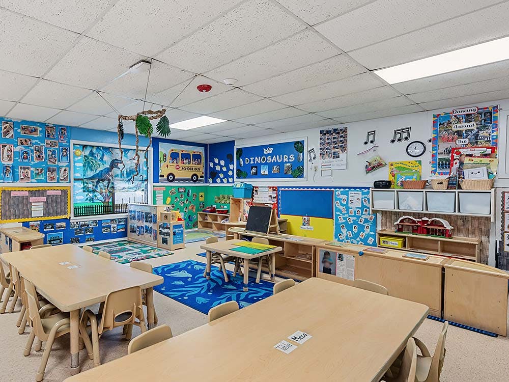 Empty classroom with small tables and chairs, decorated walls with educational posters
