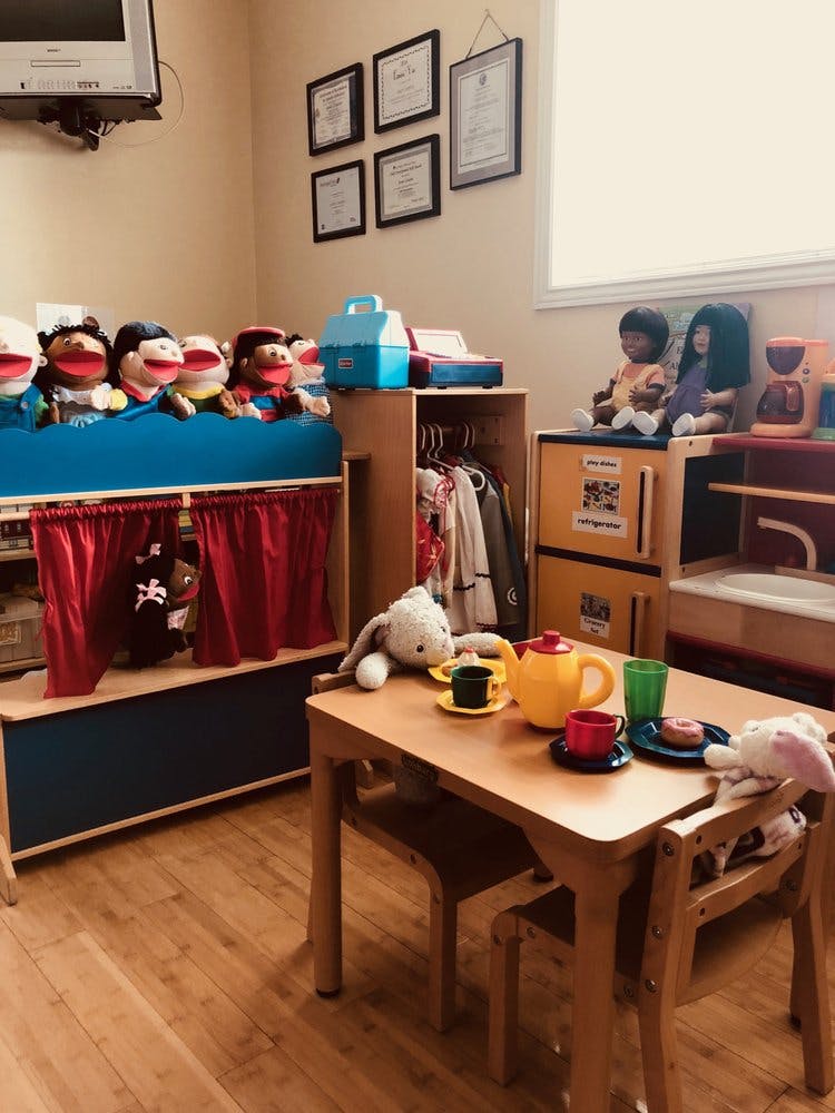 Playroom with puppet theater, dolls, and small table with toy tea set