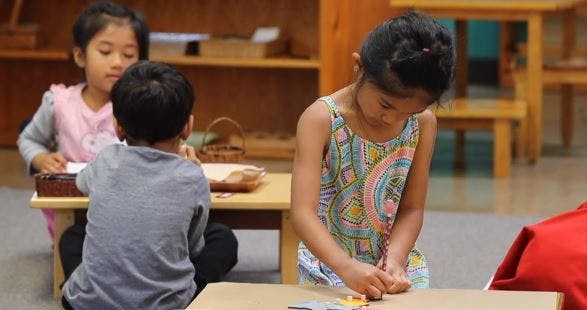 Three children working at small tables in a classroom