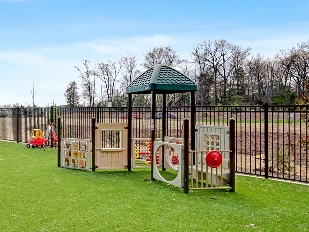 Small outdoor playground area with a play structure on artificial turf