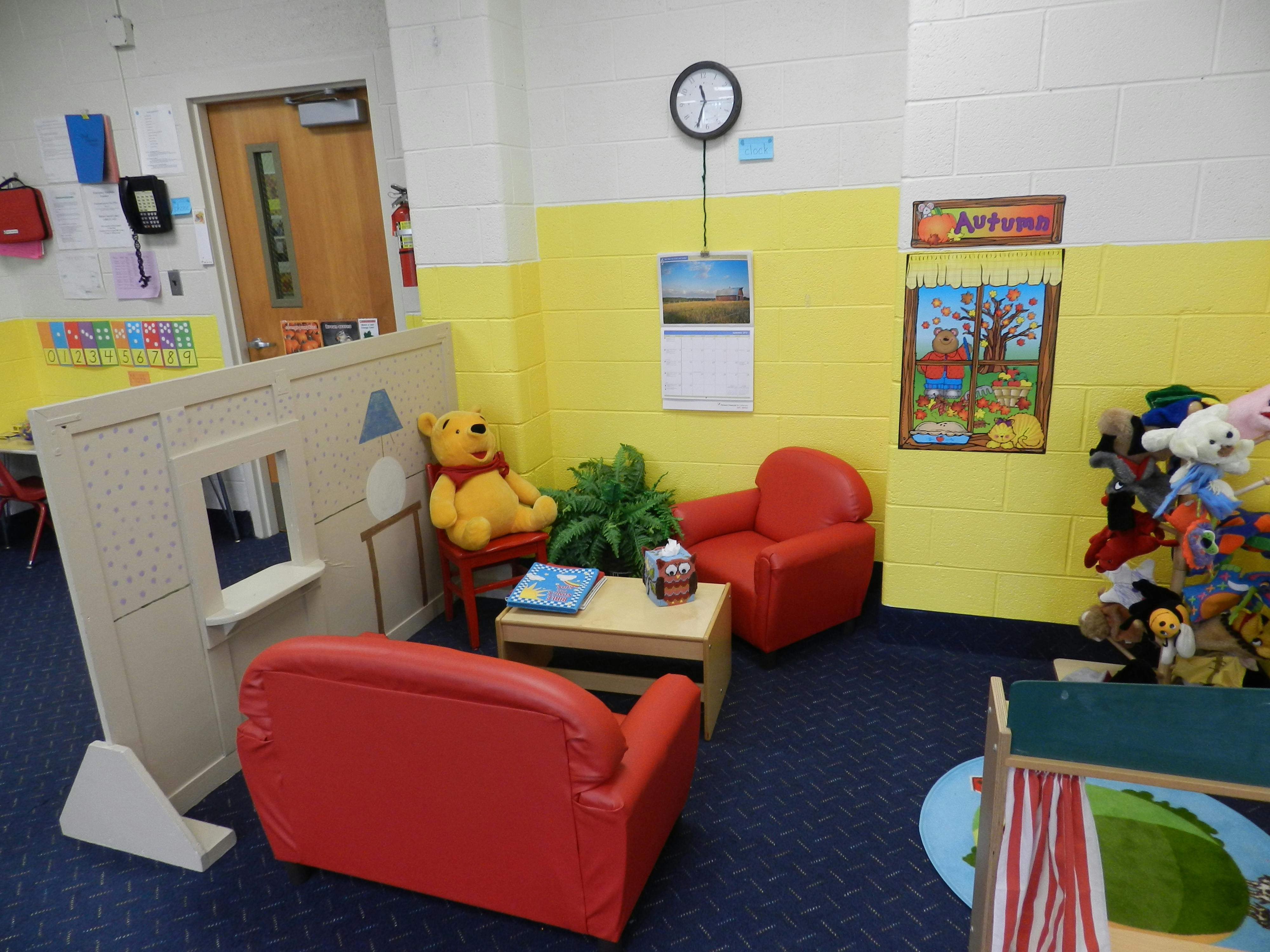 Playroom with small red chairs, a toy house, and stuffed animals