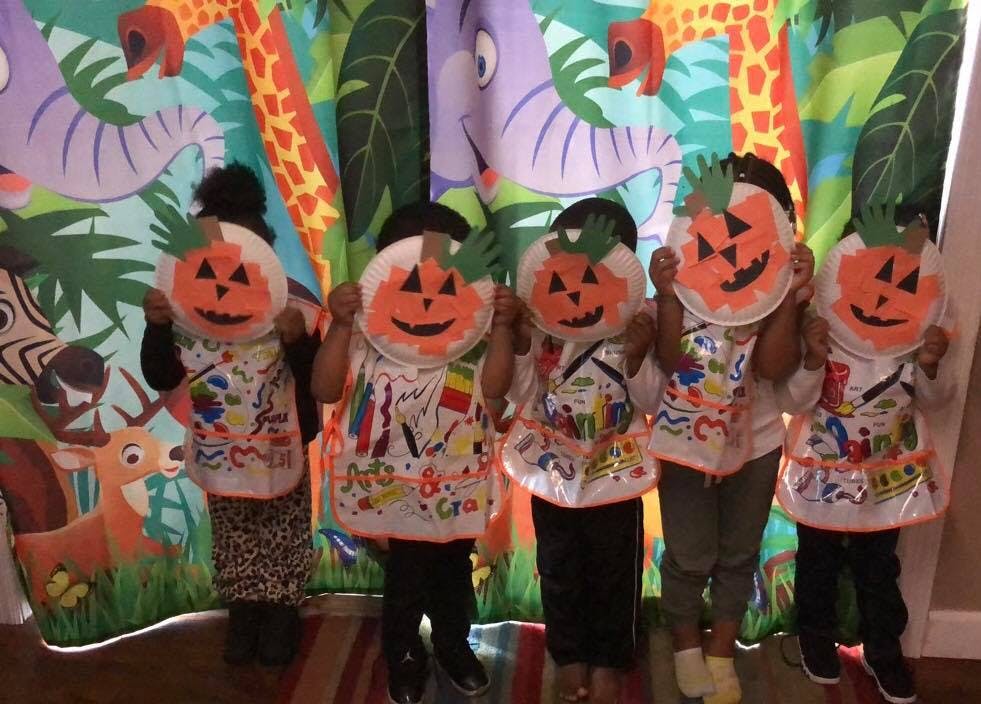 Five children holding up pumpkin crafts in front of their faces