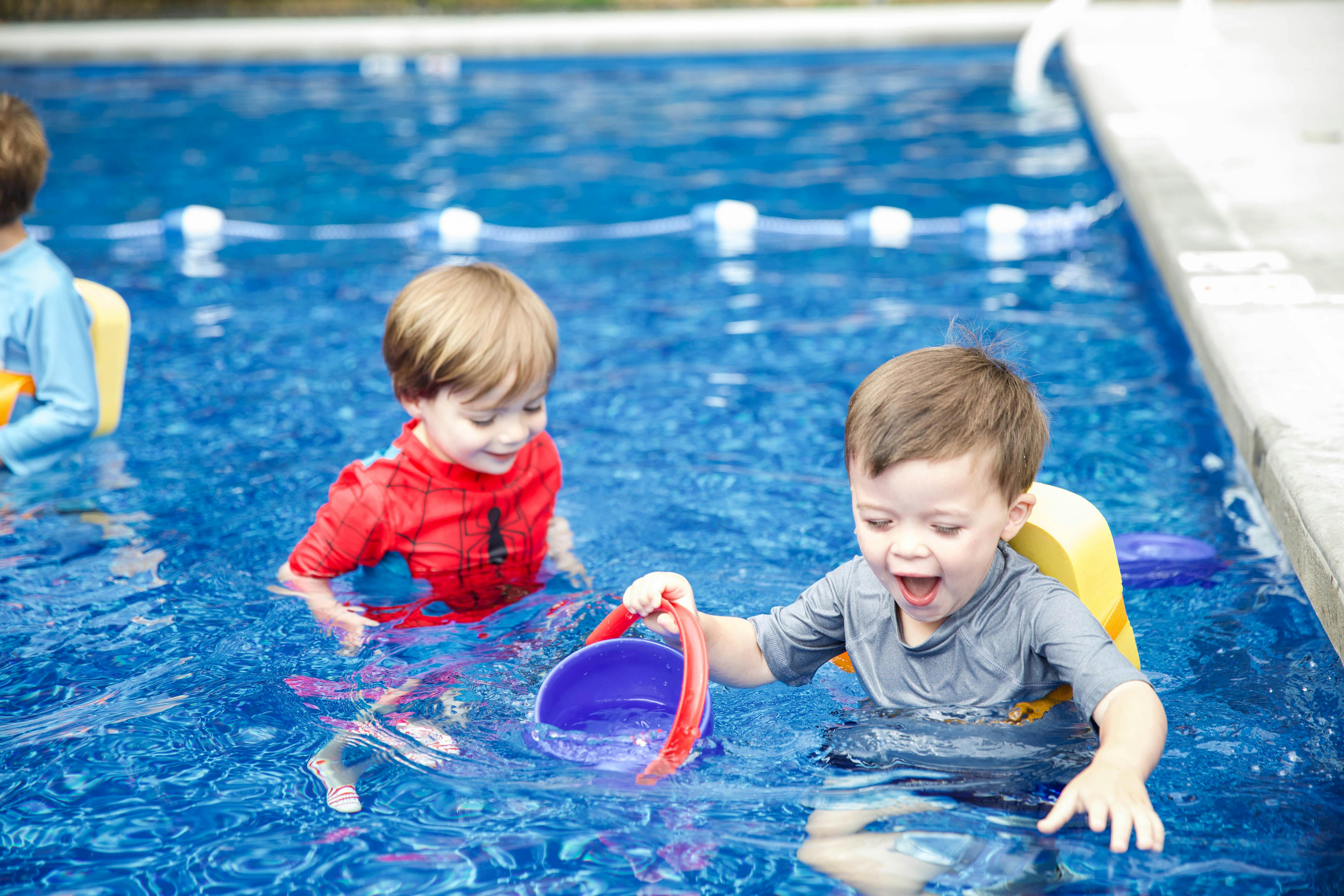 Children playing with a bucket in a swimming pool