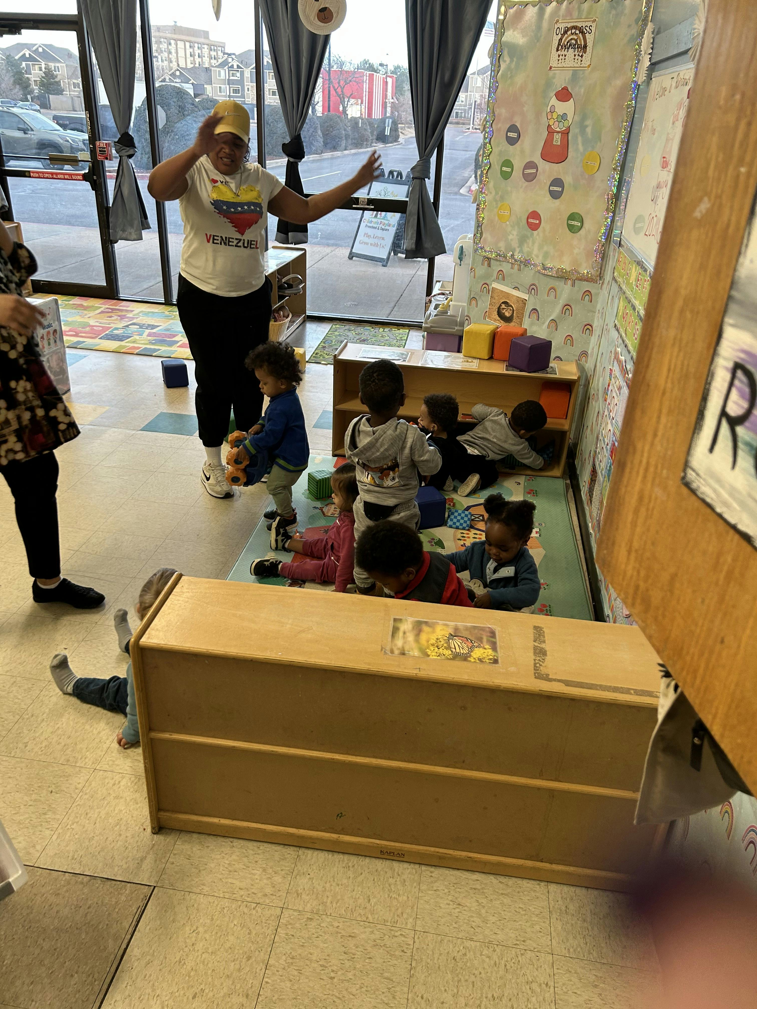 Adult person with children playing in a classroom, with text "Children's Playland"