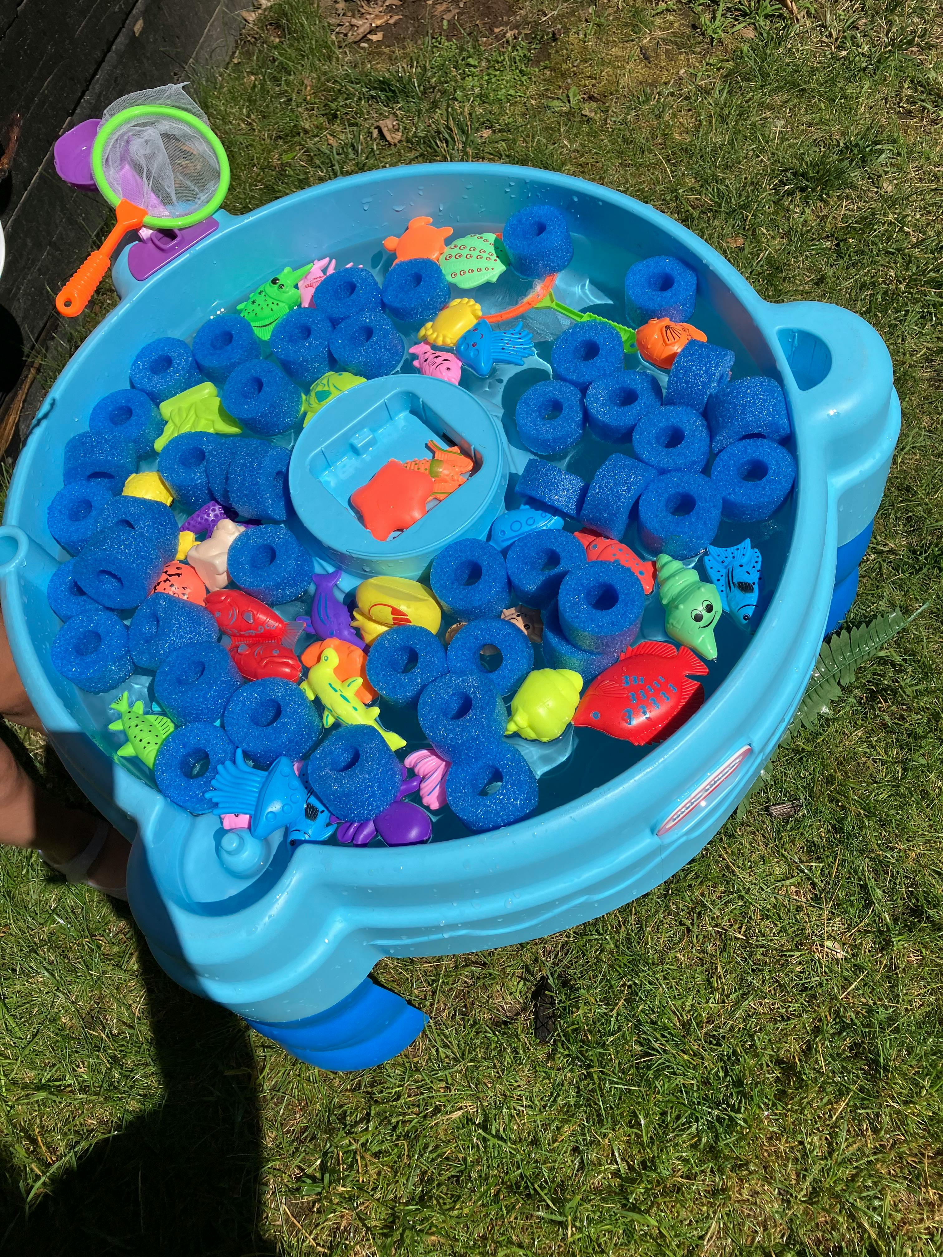 Water table filled with water, blue foam rings, and colorful plastic toys