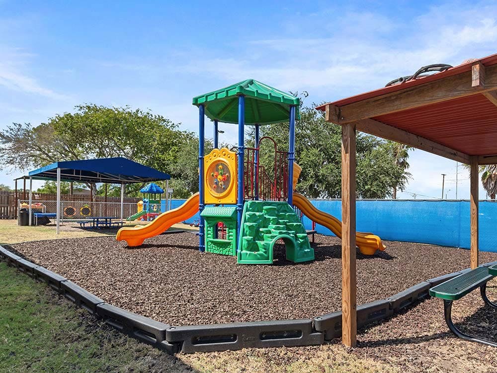 Playground with colorful play structure, slides, and blue canopy