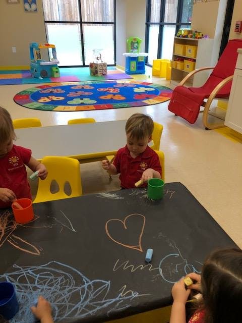 Children drawing with chalk on a black table in a classroom