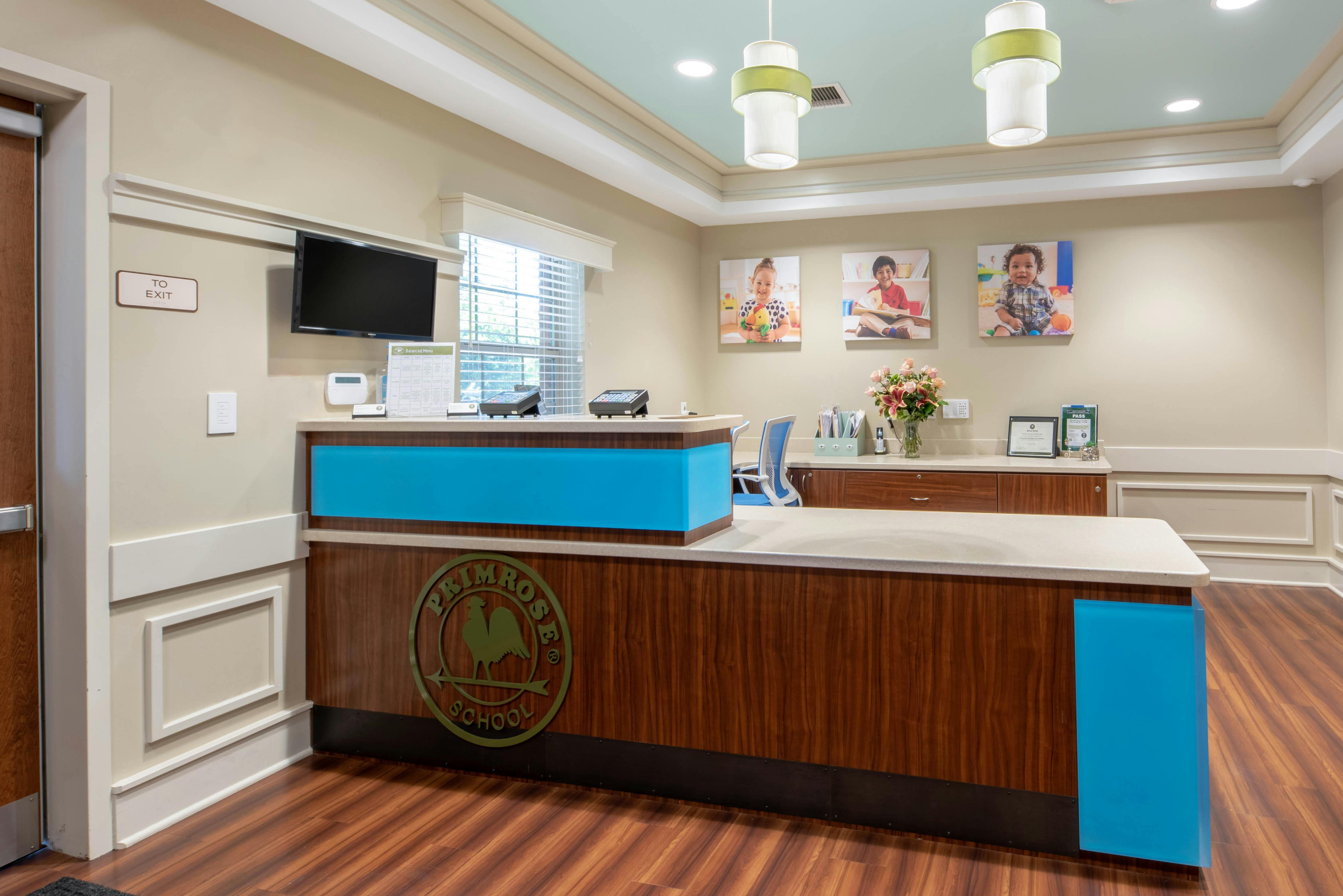 Reception desk with wood and blue panels and a Primrose School logo on the front