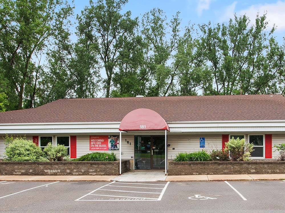Exterior of a single-story building with a red awning and parking spaces