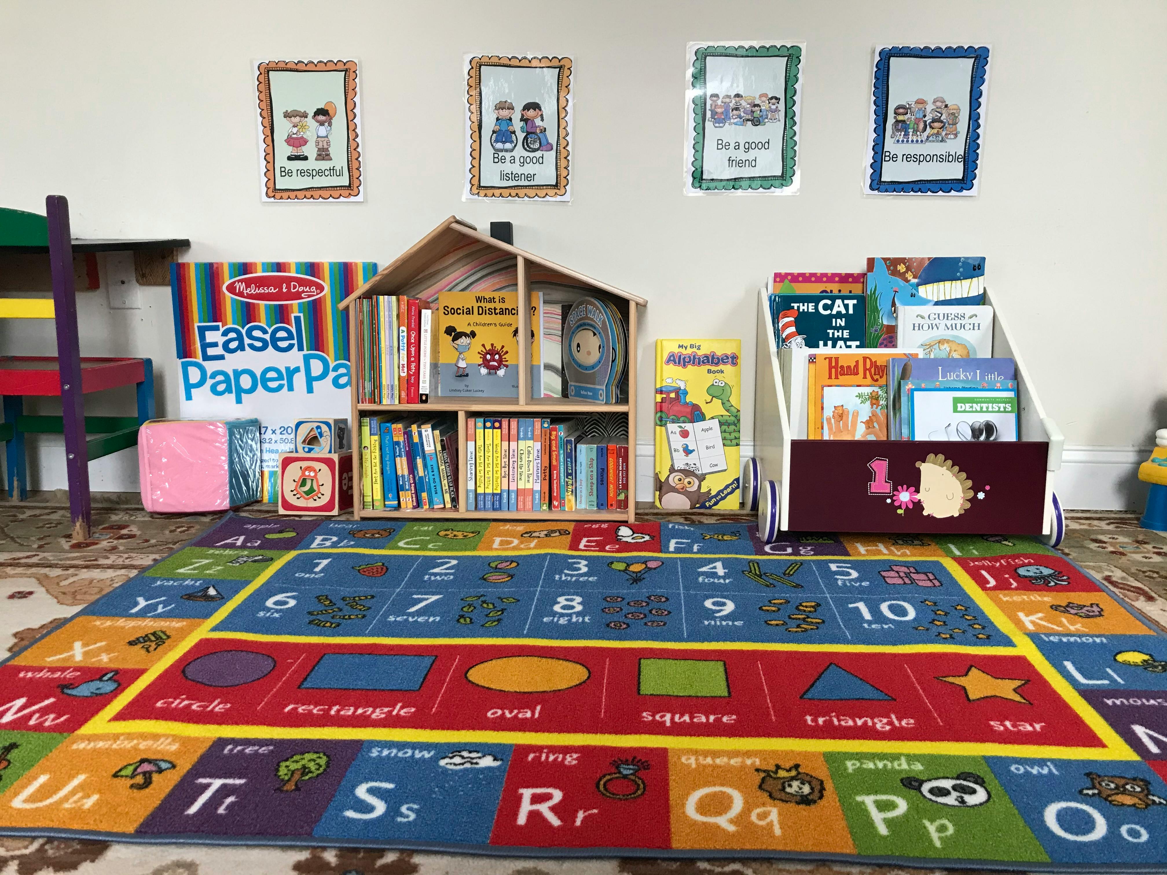 Children's play area with a colorful alphabet rug, bookshelves, and toys
