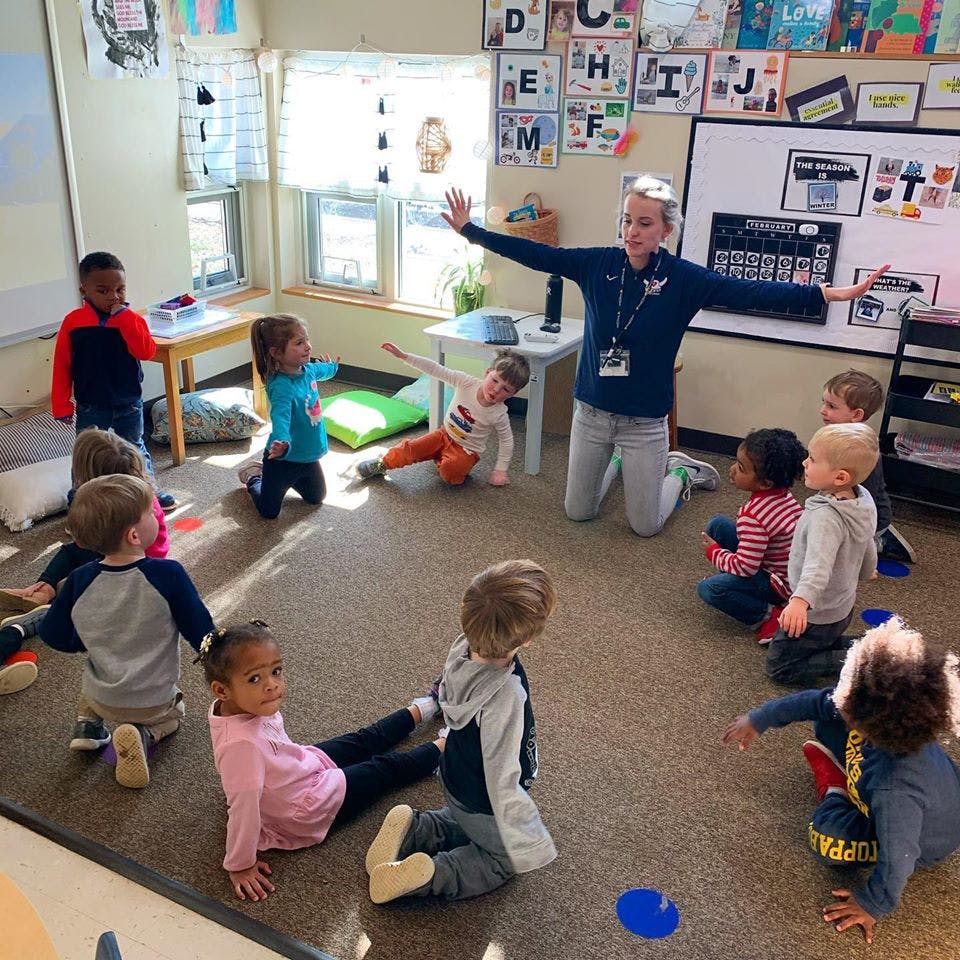 Adult leading a group of children in a classroom activity